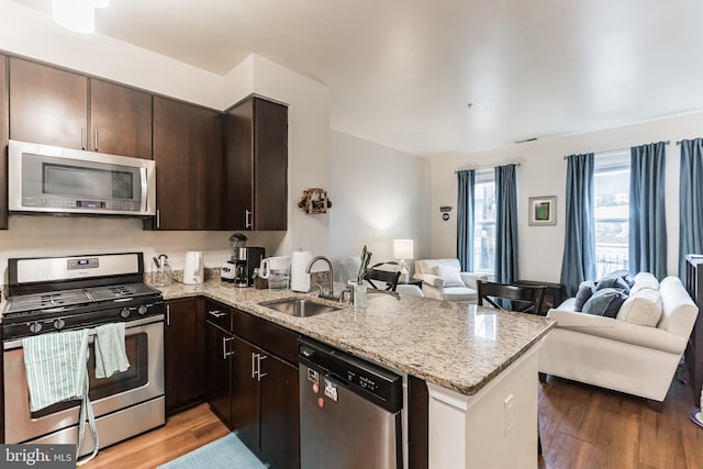 kitchen featuring light hardwood / wood-style floors, appliances with stainless steel finishes, kitchen peninsula, and sink