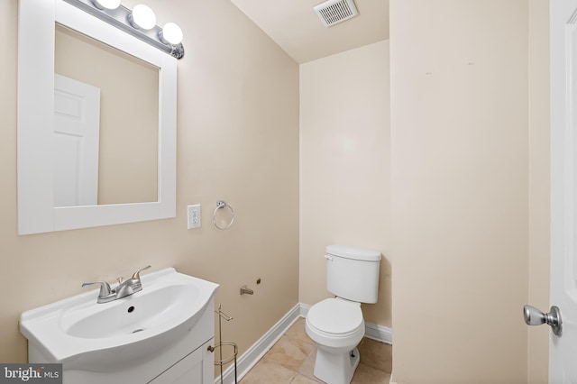 bathroom with toilet, vanity, and tile patterned floors