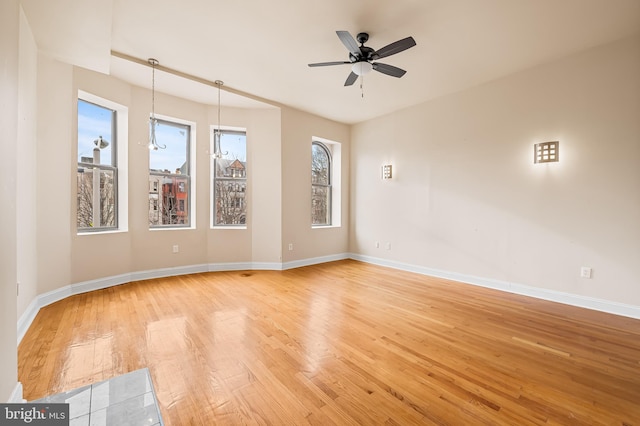 spare room featuring ceiling fan with notable chandelier and light hardwood / wood-style flooring