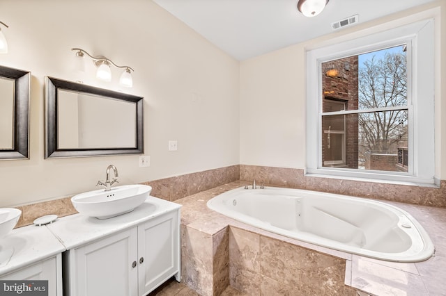 bathroom featuring tiled bath and vanity