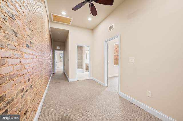 hall with light carpet, brick wall, and a high ceiling