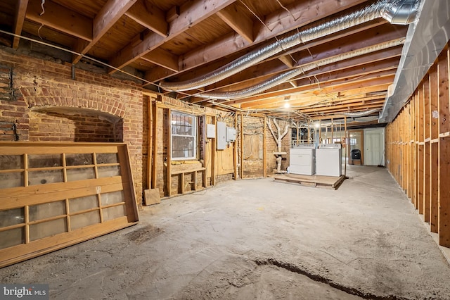 basement featuring brick wall and independent washer and dryer