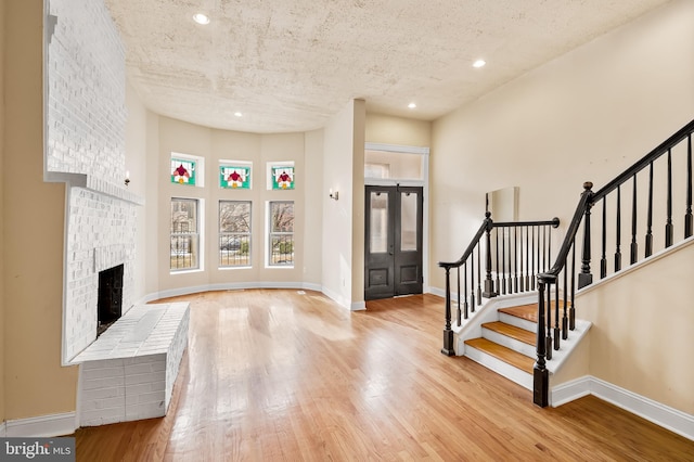 entryway featuring a brick fireplace, a textured ceiling, and light hardwood / wood-style flooring