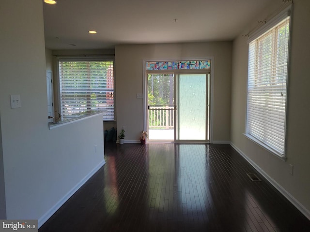 unfurnished room featuring dark hardwood / wood-style flooring and plenty of natural light