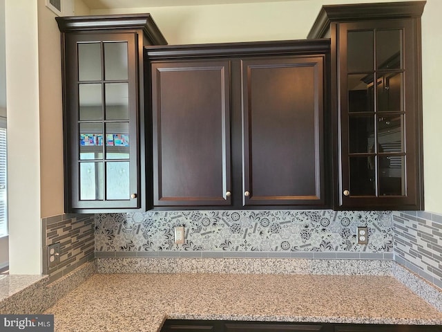 details with light stone countertops, dark brown cabinets, and tasteful backsplash