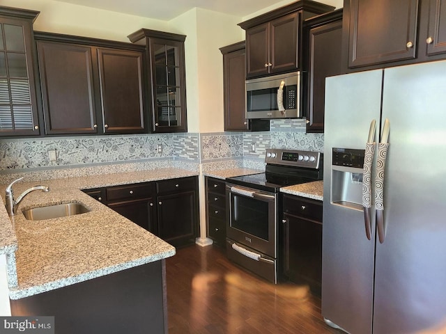 kitchen featuring sink, light stone counters, backsplash, dark hardwood / wood-style flooring, and appliances with stainless steel finishes