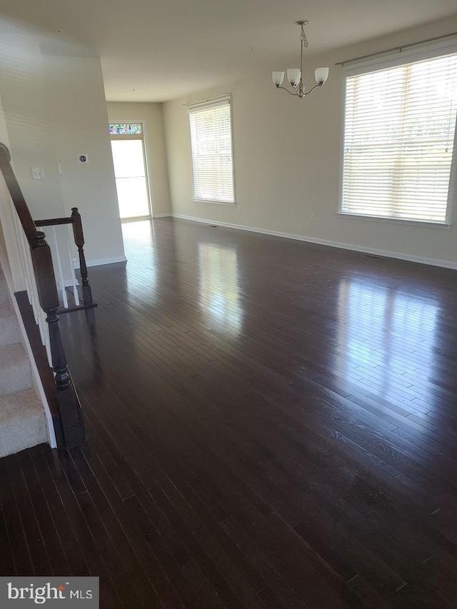 unfurnished living room with dark wood-type flooring and a chandelier