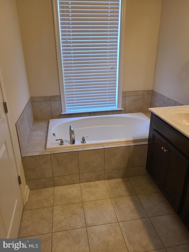 bathroom featuring a relaxing tiled tub, tile patterned floors, and vanity