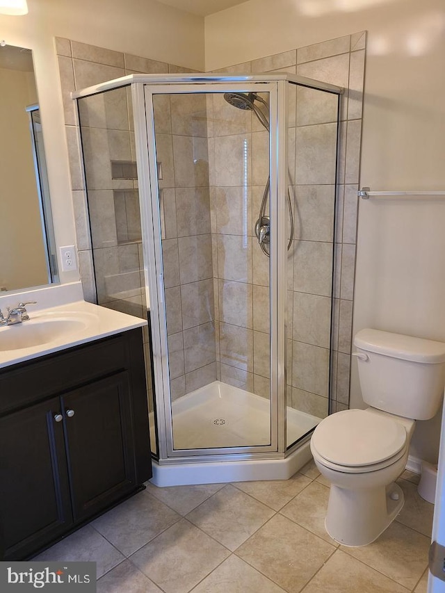 bathroom with toilet, vanity, a shower with shower door, and tile patterned floors