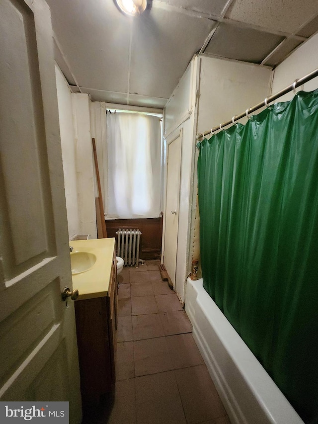 bathroom with radiator heating unit, shower / tub combo, vanity, and a paneled ceiling