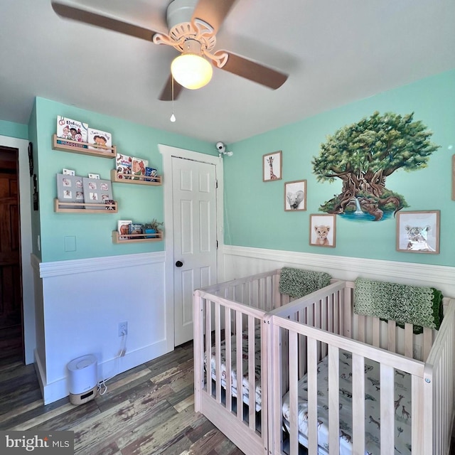 bedroom with ceiling fan, hardwood / wood-style flooring, and a nursery area