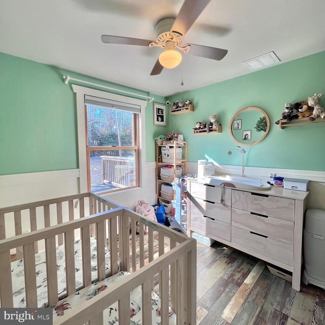 bedroom with ceiling fan, sink, a crib, and dark hardwood / wood-style floors