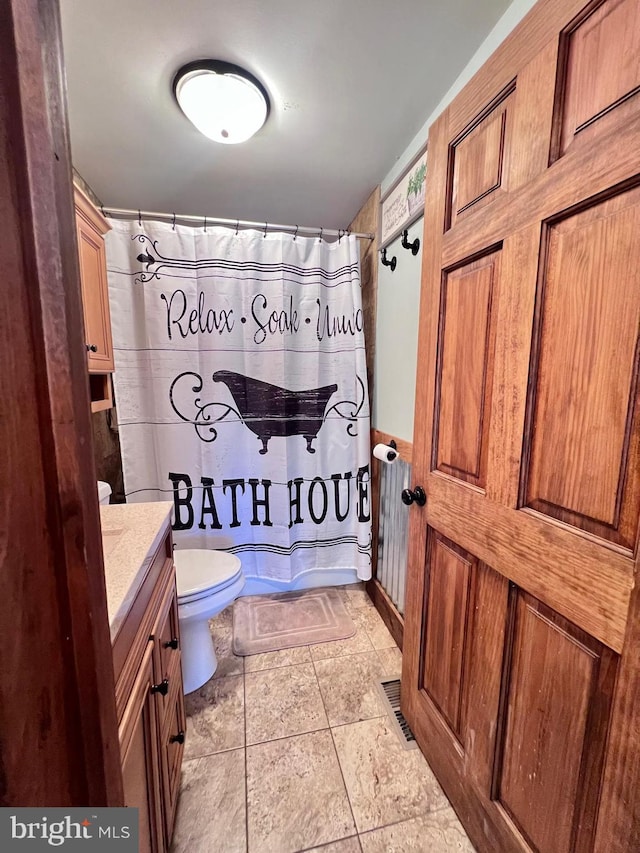 bathroom featuring a shower with shower curtain, vanity, and toilet