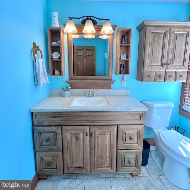 bathroom with toilet, vanity, and tile patterned flooring