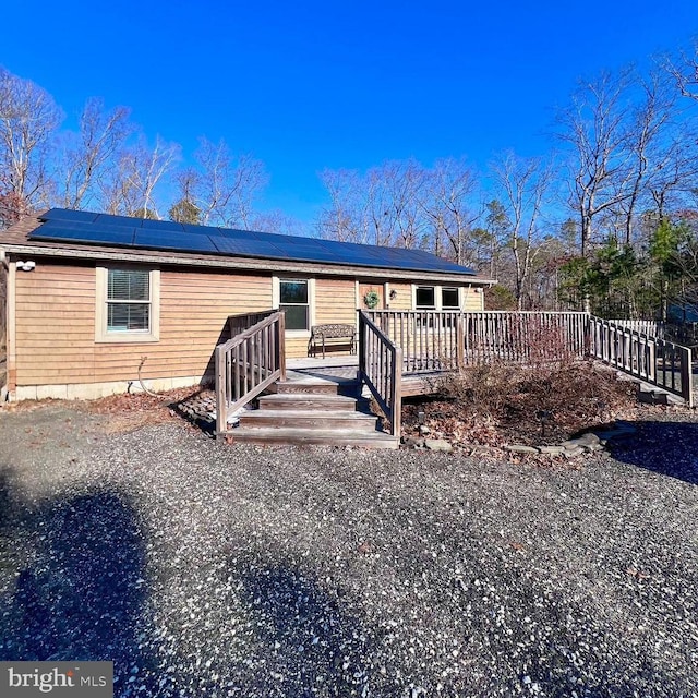 back of property with solar panels and a wooden deck