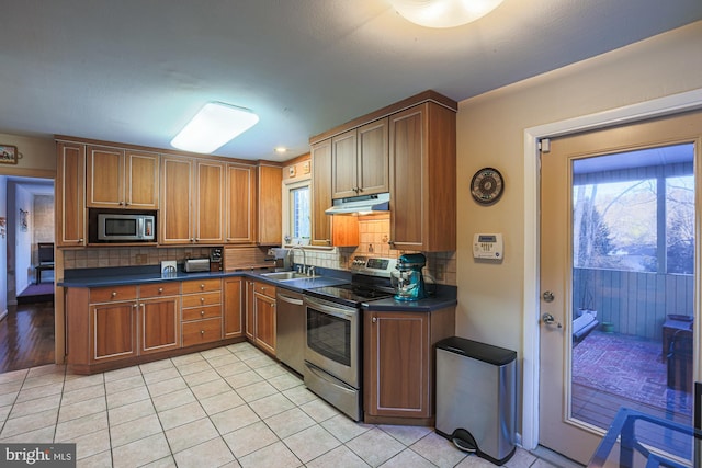 kitchen with stainless steel appliances, decorative backsplash, sink, plenty of natural light, and light tile patterned flooring