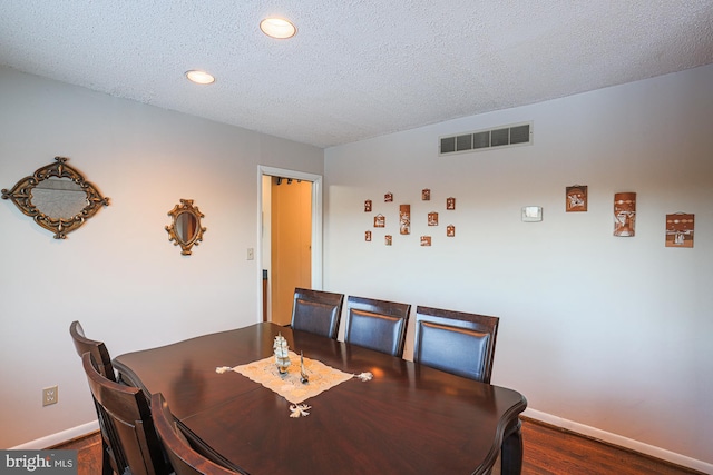 dining area featuring a textured ceiling and dark hardwood / wood-style flooring