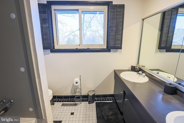 bathroom with toilet, vanity, and tile patterned flooring