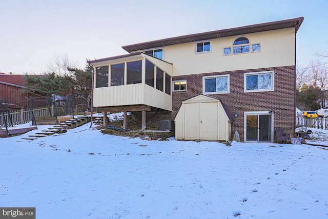 snow covered property with a sunroom and cooling unit