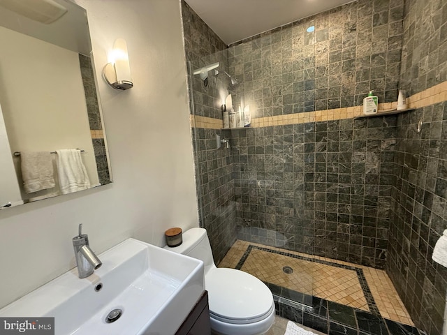 bathroom featuring toilet, tiled shower, and vanity