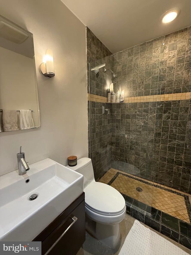 bathroom featuring toilet, vanity, and a tile shower