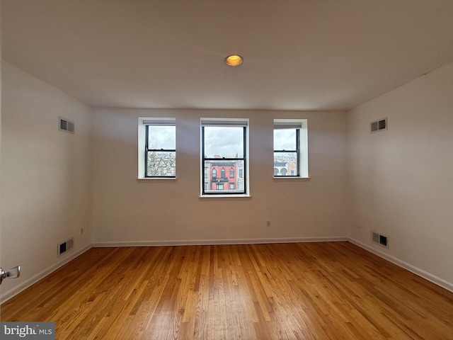 unfurnished room with light wood-type flooring and visible vents