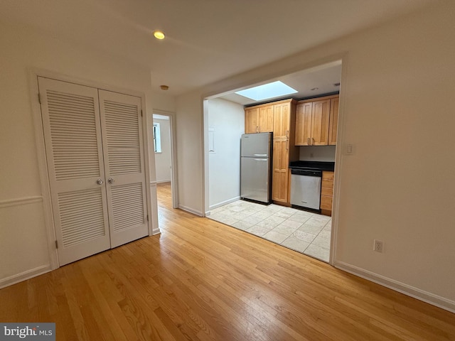 kitchen featuring stainless steel appliances, dark countertops, light wood-style flooring, and baseboards