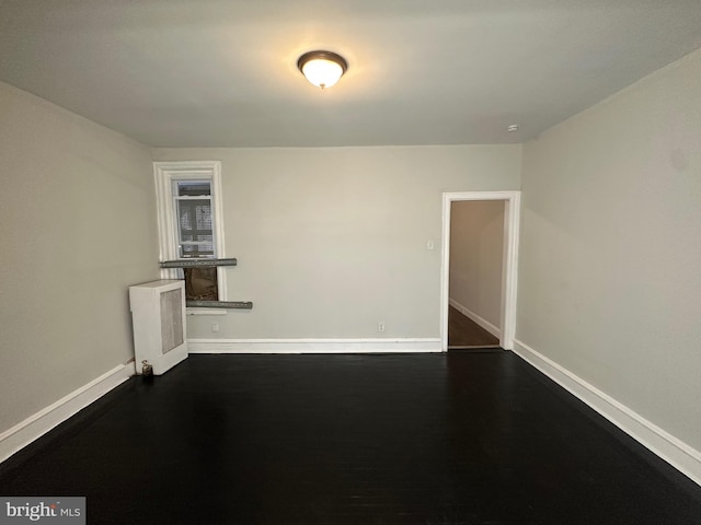 spare room with dark hardwood / wood-style flooring and radiator