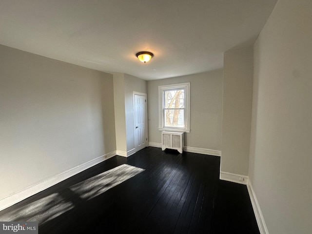 unfurnished room featuring dark wood-type flooring and radiator