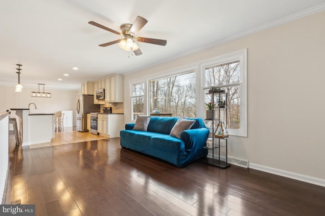 sitting room with visible vents, baseboards, wood finished floors, and ornamental molding