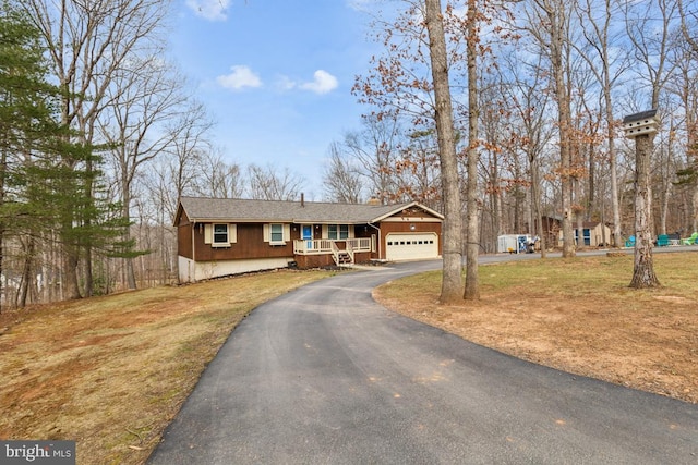 view of front facade featuring a porch, aphalt driveway, a front lawn, and an attached garage