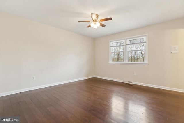 unfurnished room featuring dark wood-style floors, visible vents, baseboards, and a ceiling fan