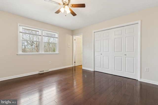 unfurnished bedroom with baseboards, visible vents, a ceiling fan, dark wood-style floors, and a closet