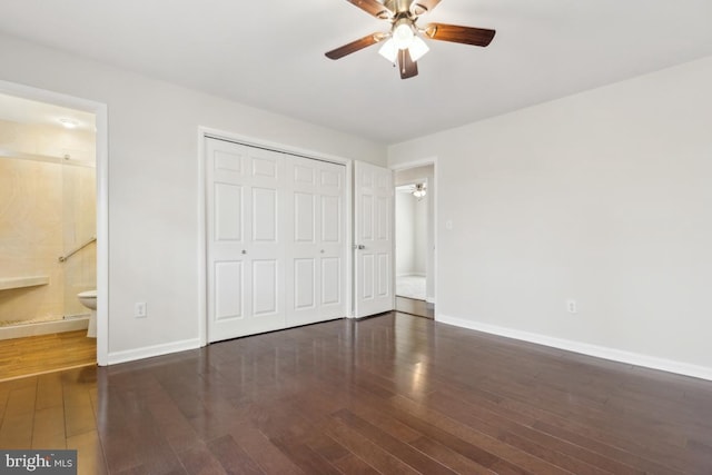 unfurnished bedroom with ensuite bathroom, a closet, wood finished floors, and baseboards