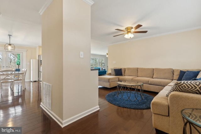 living room with visible vents, ornamental molding, and dark wood finished floors