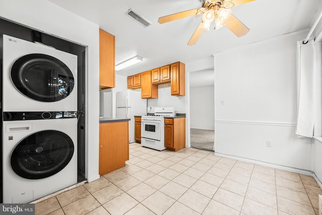 kitchen with ceiling fan, white appliances, light tile patterned floors, and stacked washer / dryer