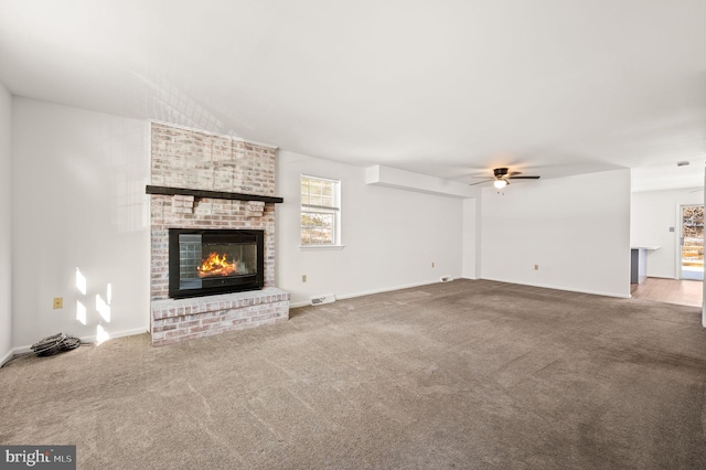 unfurnished living room featuring carpet, ceiling fan, and a brick fireplace