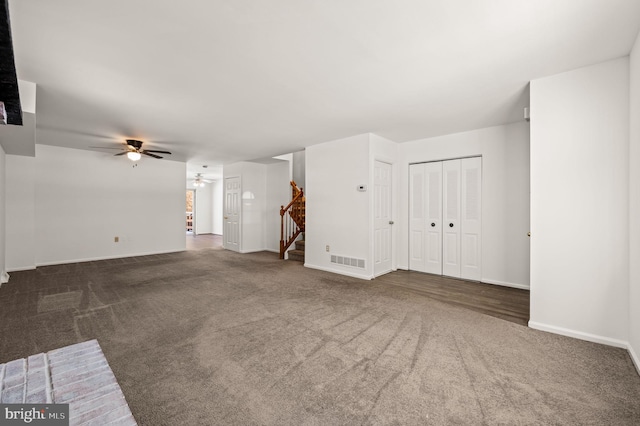 unfurnished living room featuring dark carpet and ceiling fan