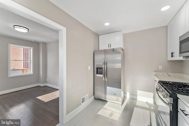 kitchen with light stone counters, stainless steel appliances, and white cabinets