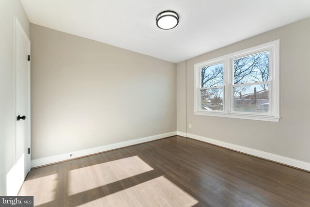 unfurnished room with dark wood-type flooring