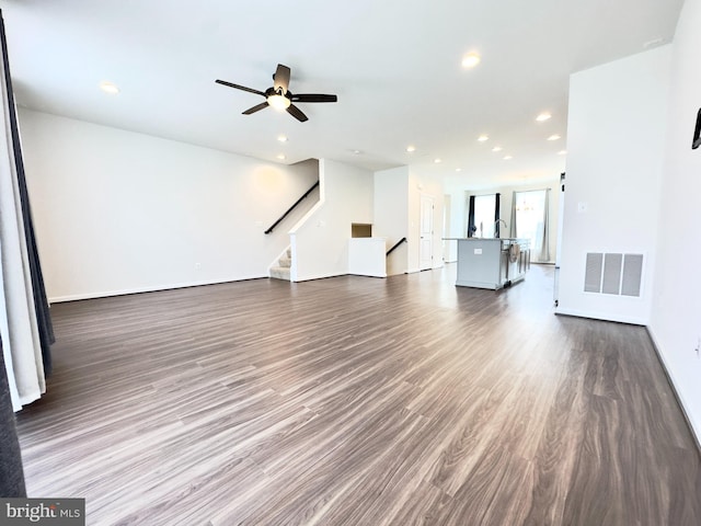 unfurnished living room with ceiling fan and dark wood-type flooring