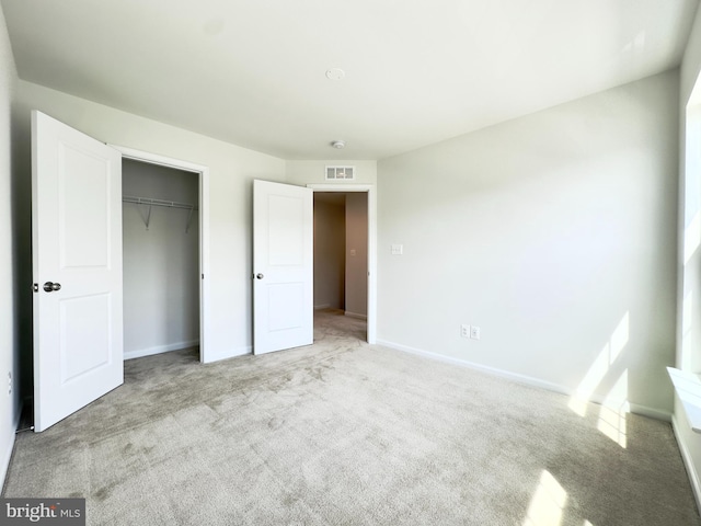 unfurnished bedroom with a closet and light colored carpet