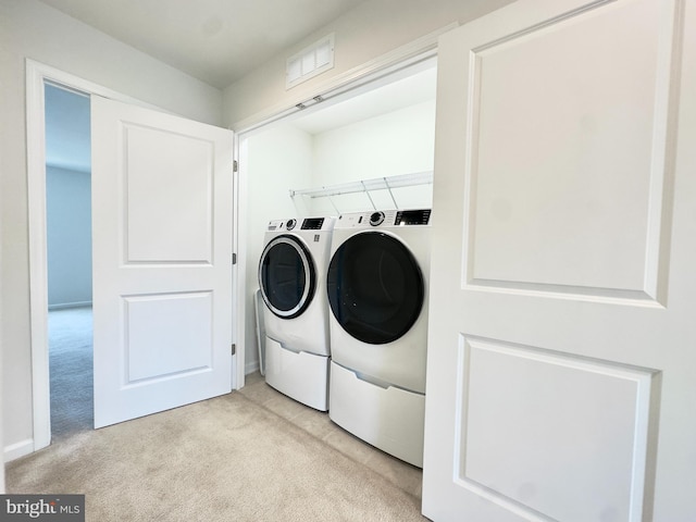 laundry area featuring light colored carpet and washing machine and clothes dryer