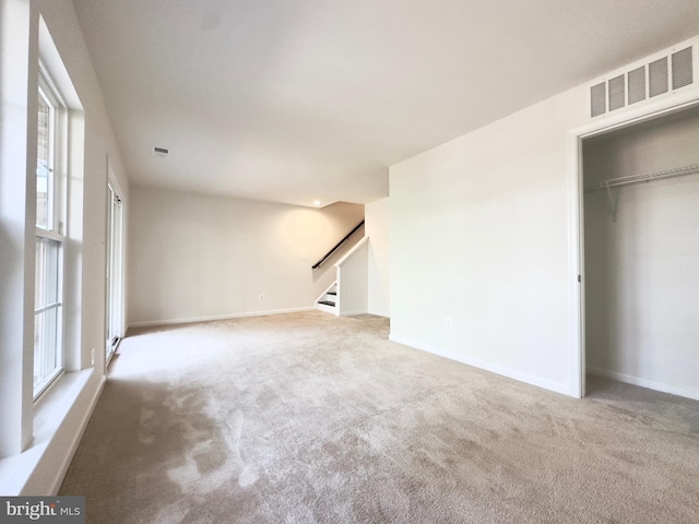 unfurnished living room with carpet floors and a wealth of natural light