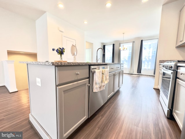 kitchen featuring a kitchen island with sink, appliances with stainless steel finishes, gray cabinetry, dark wood-type flooring, and decorative light fixtures