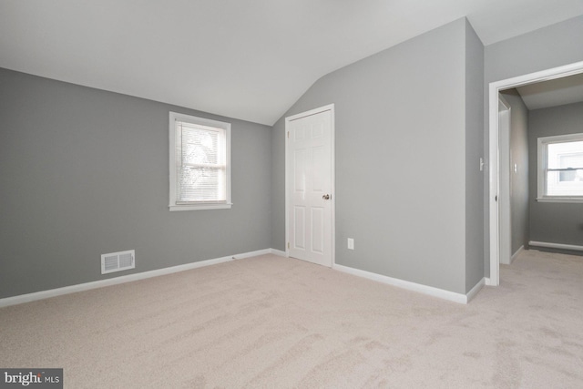 carpeted spare room with vaulted ceiling