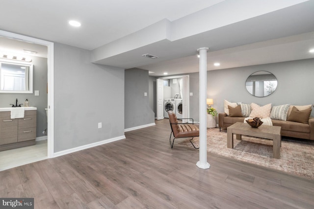 living room with sink, independent washer and dryer, and wood-type flooring