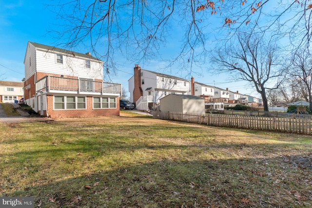 rear view of property featuring a balcony, a yard, and a shed