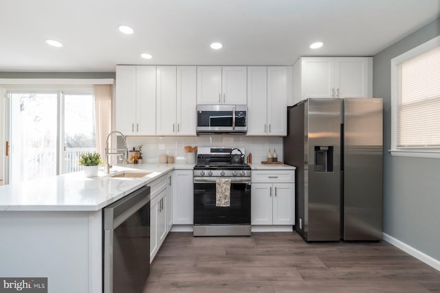 kitchen featuring sink, stainless steel appliances, white cabinetry, and backsplash