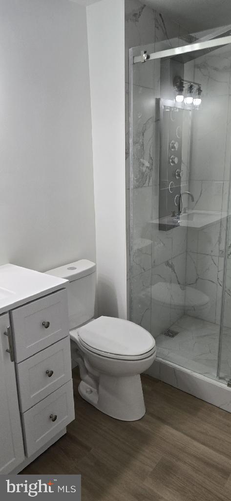 bathroom featuring toilet, vanity, a shower with shower door, and hardwood / wood-style floors